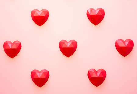 Holiday background for Valentine's Day, Red polygonal paper heart shapes on a cream background. Love concept. Plain. Minimalistic styleの写真素材
