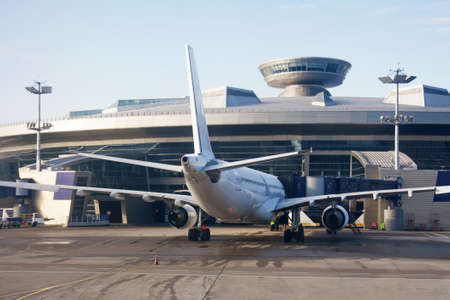 Jet passenger airplane with a ramp parked at the airport against the background of the terminal...