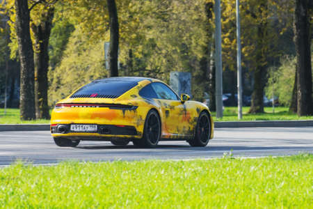 Yellow Porsche 911 Carrera driving along the city street. Russia.Saint-Peterburg, 14 may 2020