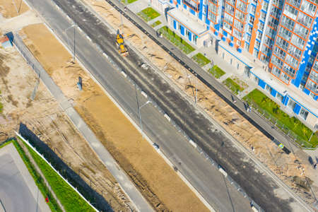 Construction of a city street, laying of communications, installation of sewer hatches, gutters, curbs improvement of the street, after laying asphalt. Preparation for paving, aerial viewの写真素材