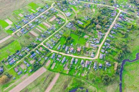 Beautiful small green village from above, dirt roads, streets, vegetable gardens, plowed fields, meadows, houses. Aerial top viewの写真素材