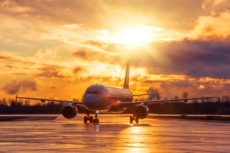 Airplane on airport runway under sunset view dramatic sky after the evening rainの写真素材