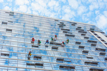 Climbers clean windows from the outside of the building washing the glazing of the facade of a multi-storey buildingの写真素材