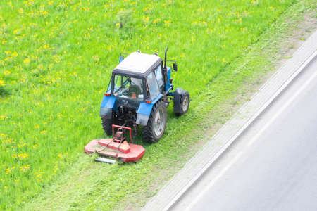 Tractor uses trailed lawn mower to mow grass on city lawns, aerial viewの写真素材