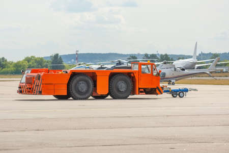 Aerodrome orange tow tractor is driving along the steering paths at the airportの写真素材