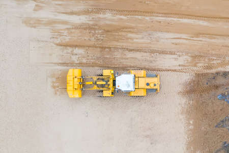 Aerial view of the working yellow earth mover grader flattens the surfaceの写真素材