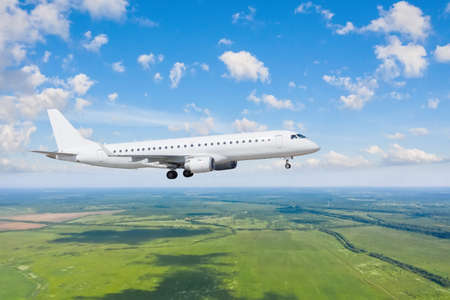 Commercial airplane flying approach with landing gear extended above cloudscape in day sun light