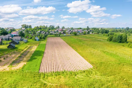 Beautiful small green village and a plowed field nearby summer from aboveの写真素材