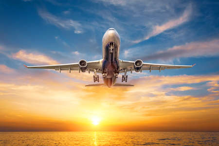 Airliner flying approaching over the sea surface at sunset tropical sunsetの写真素材