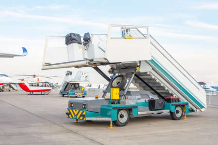 Machine mobile ladder stairs at the airport on the airfield in the distance planes and helicoptersの写真素材