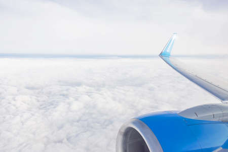 Wing of the engine aircraft in the air with clouds in sky and horizon on the backgroundの写真素材