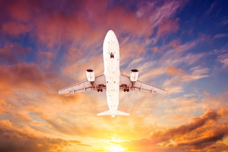 Airplane flying overhead during a black sunsetの写真素材