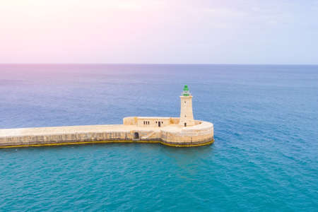 Lonely lighthouse on a stone pier in the seaの写真素材