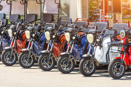 Electric scooters, three-seater mopeds at the parking lot for rental and movement around the cityの写真素材