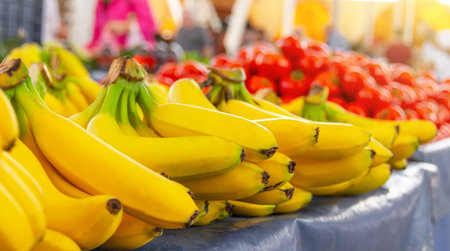 Yellow ripe bananas lie on a market stall with other fruits in the backgroundの写真素材