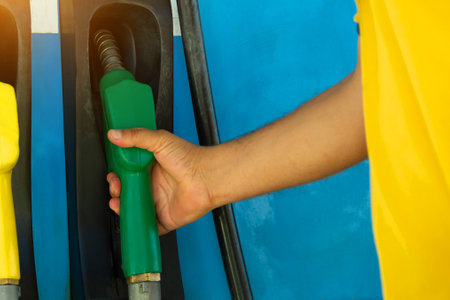 Man holds a refueling gun in his hand for refueling cars. Gas station with diesel and gasoline fuel close-upの写真素材