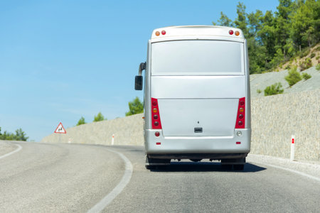 Big tourist bus rides along a mountain road with a protective wallの写真素材