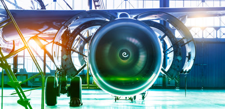 Repair maintenance of aircraft engine open hood on the wing of the plane. Industrial theme view in blue-green hue with bright sources of warm light. Format banner header wide size, place sample textの写真素材