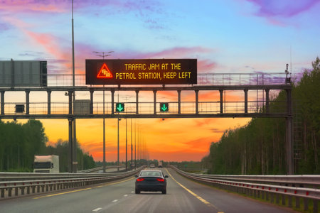 The inscription on electronic scoreboards warning traffic jam et the petrol station keep left over a high-speed highway in the evening on the highwayの写真素材