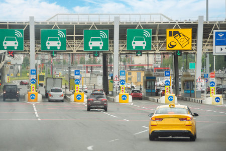 View with cars at the entrance or exit to a toll road limited by a barrier. Cashless payment transponder barrier, speed limit signsの写真素材