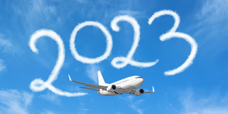 Happy New year 2023 on the background below cloudscape. Drawing by passenger airplane vapor contrail in sky. Concept of travel in the new year, holidaysの写真素材