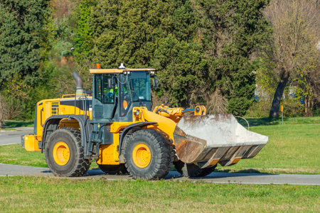 Grader and Excavator Construction Equipment on the background of trees rides on the road