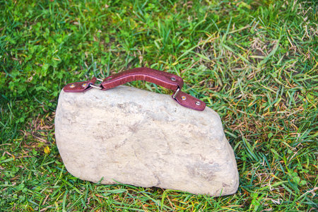 Women's handbag with a leather handle in the form of a stone. Concept of heavy bags in which there are a lot of things and it is difficult to find what you need, heavy burdenの写真素材