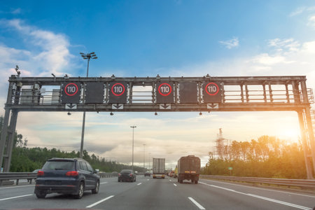 Dense stream of trucks and cars on a highway with speed signs of 110 km per hour in the morning at sunriseの写真素材