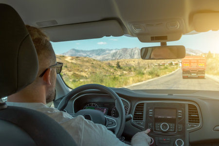 Person driving car, driver at the wheel adjusts the volume of the music and drives along a country roadの写真素材