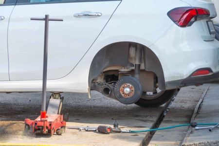 Rear wheel removed, lifted by hydraulic jack, car repair on the roadside