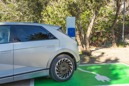 Electric car charging station for charge plug EV battery. Clean energy. Charging green area point at car parking lot. Future transport technologyの写真素材