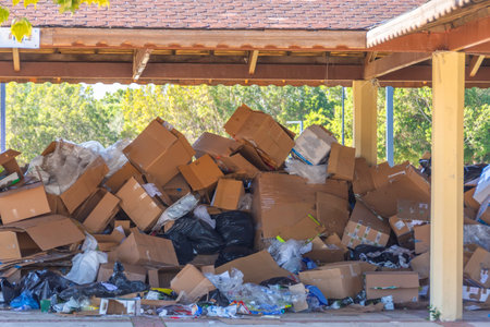 Discarded brown colored corrugated paper carton boxes piled up for recycle process. Under a wooden canopy, ready for removal and disposalの写真素材