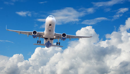 Airplane flying over takes off with the landing gear extended against the background of the sky and cloudsの写真素材