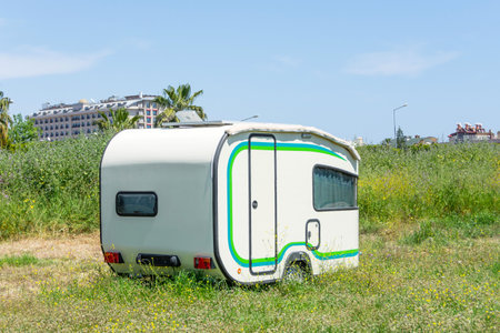 Mobile home trailer on wheels van parked in the street on the meadow of the city park