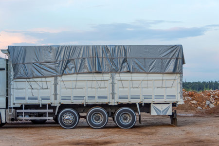 Truck with a white body with sides covered with a gray tarpaulin rain protectionの写真素材