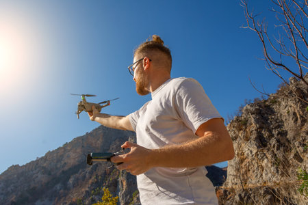 Young man launches a drone into the air to fly in the mountains