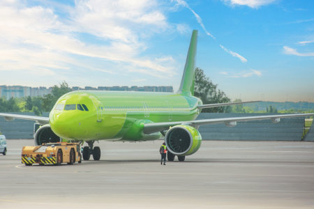 The green plane pushes the tow tractor before starting the engines and taxiing, front view