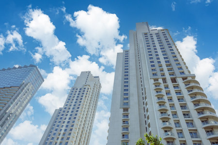 Look up at urban buildings, residential skyscrapers, cumulus white clouds sky blue view up