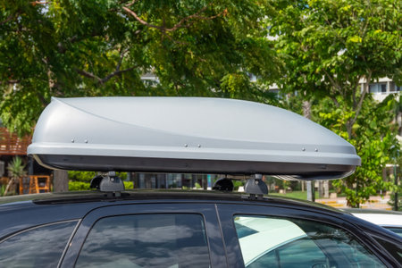 Black plastic car rooftop cargo box or roof carrier for traveling. Removable storage container mounted on car roof rack.の写真素材