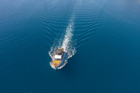 View from a height of a white speedboat sailing in the birch sea. The motor boat leaves a mark on the water. The concept of water travel and recreationの写真素材