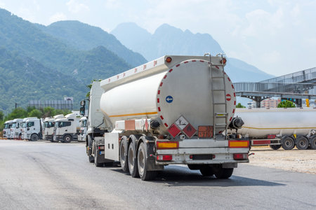 Parking row of trucks with fuel tanks in front of a warehouse and storage of huge tanks of raw material containersの写真素材