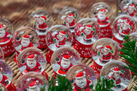 Lots of glass balls with Santa Claus and Christmas candy inside snow, fair, market.の写真素材