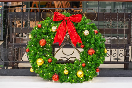Christmas wreath made of spruce with a red bow and glass balls on the fenceの写真素材