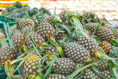 Shelf with fresh whole pineapples at grocery market. Exotic fruits from organic farms. Merchandising fruit in market buyersの写真素材
