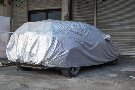Covered car on a yard in front of the garage door. Car Cover Carport Parking.の写真素材