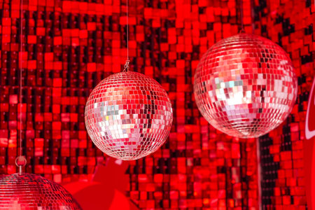Mirror disco balls suspended in a club among shiny red mosaic in the shape of squares, disco texture beautiful backgroundの写真素材