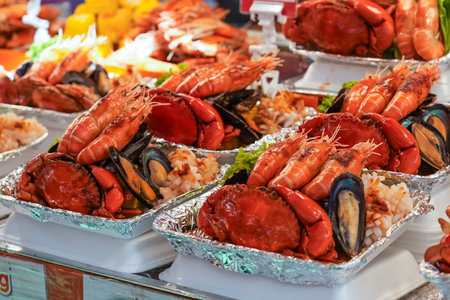 Cooked large crabs, king prawns and mussels with green salad from dishes on a street food stallの写真素材