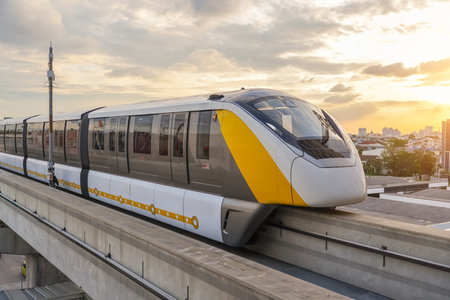 Modern high speed monorail train with bright headlights passes race station on the stage in the evening at sunsetの写真素材