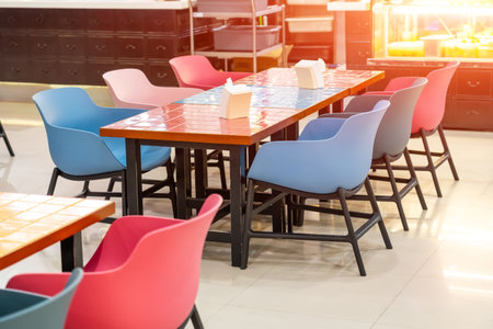Plastic chairs and wooden tables with colored bright ceramic tiles in squares
