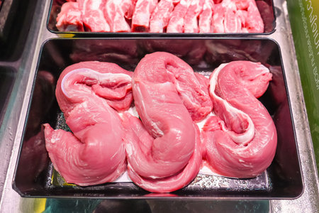 Various cuts of pork steaks, different parts of the body cutting meat for sale in containers on a...